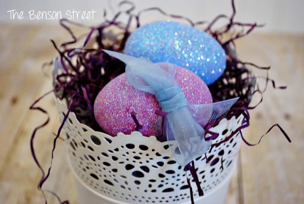 DIY Glitter Eggs in a white container with easter grass