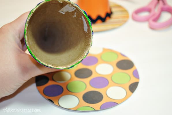 Using hot glue to attach witch hat cones to paper bottoms