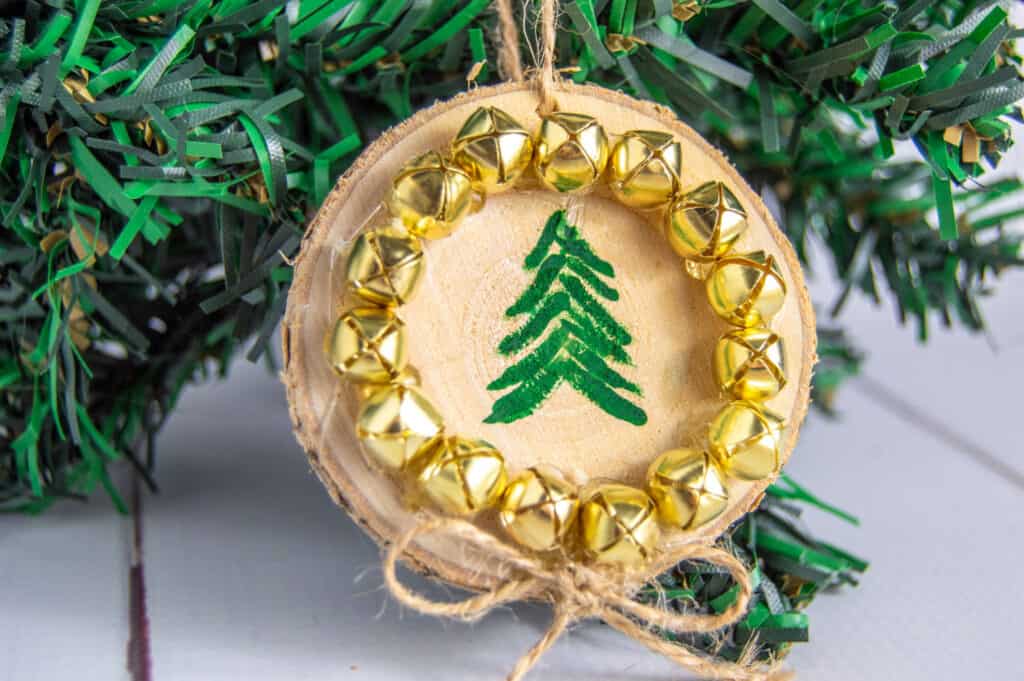 Decorate your tree with rustic charm with this simple DIY wood slice tree ornaments. Dress up the wood rounds with evergreen trees and bells for a festive dollar store craft.