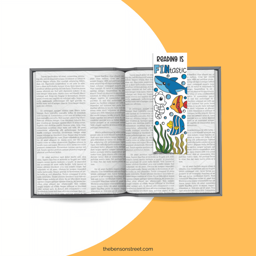 An open book with a shark coloring bookmark holding the page
