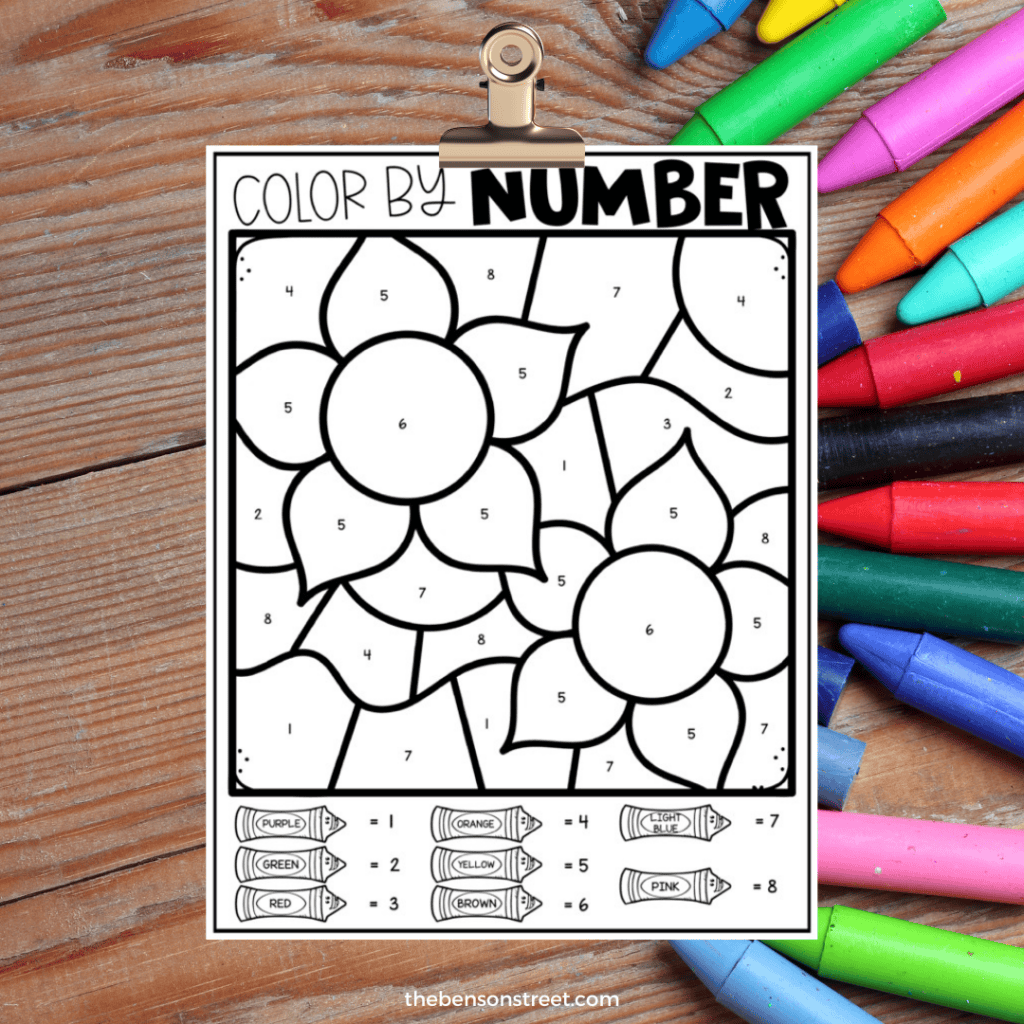 Sunflower color by number worksheet on a clipboard with crayons in the background.