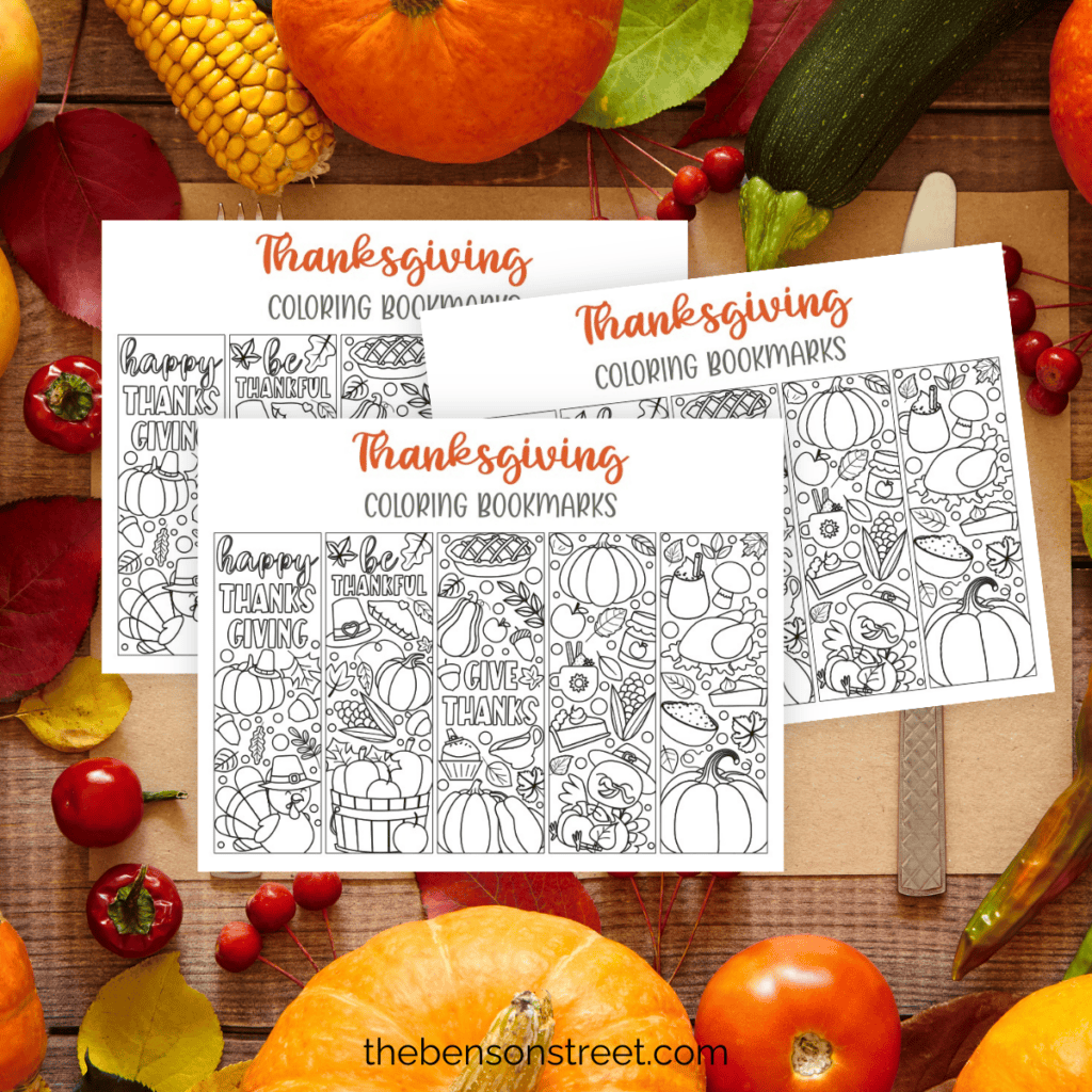 Stack of three pages of thanksgiving coloring bookmarks on a placemat with produce around.