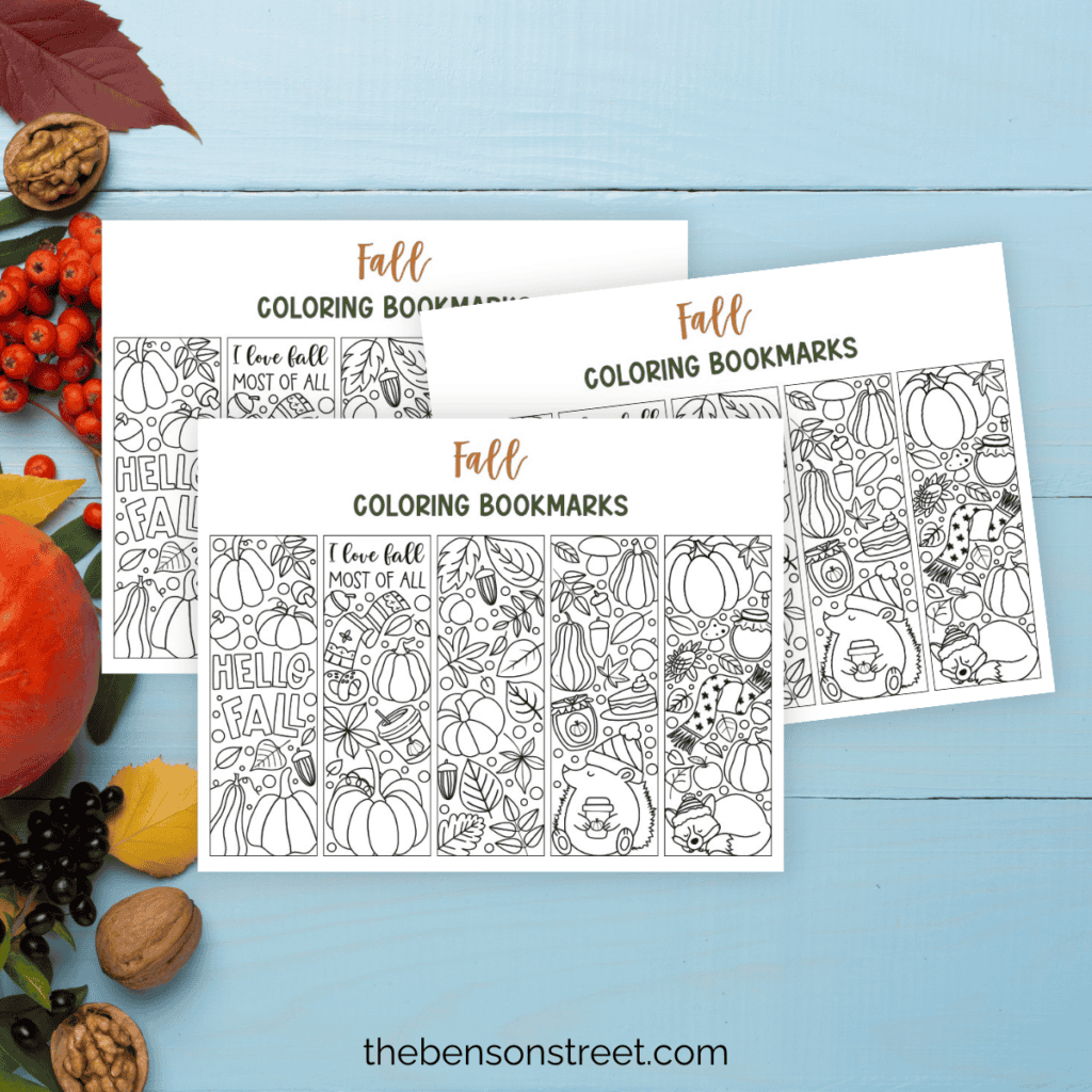 Three sheets of fall coloring bookmarks arranged on top of each other with a light blue fall background underneath.