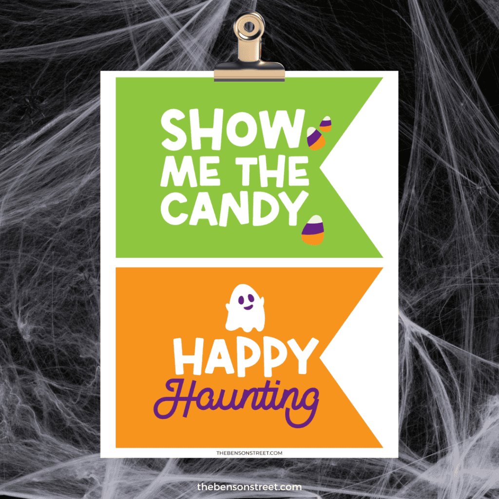 Clipboard with two Halloween party flags on a printed page. One says "show me the candy" and the other says "Happy Haunting"