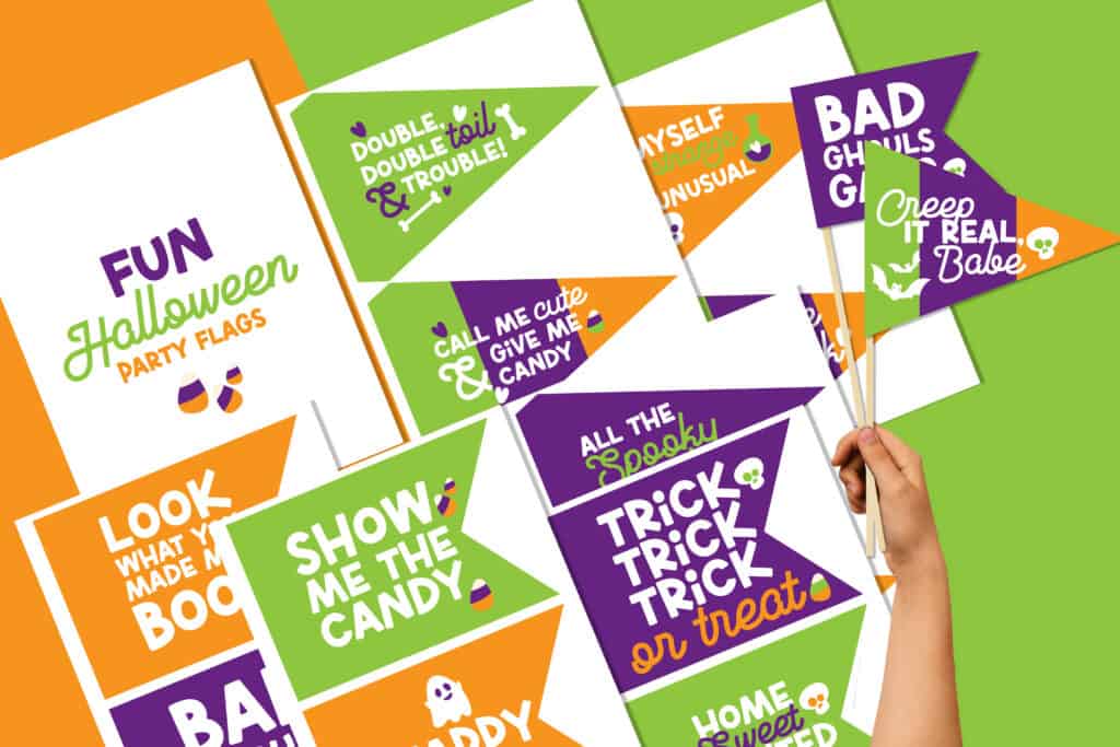 Flat lay of pages of fun Halloween party flags. Two flags are cut out and on sticks held by a hand.