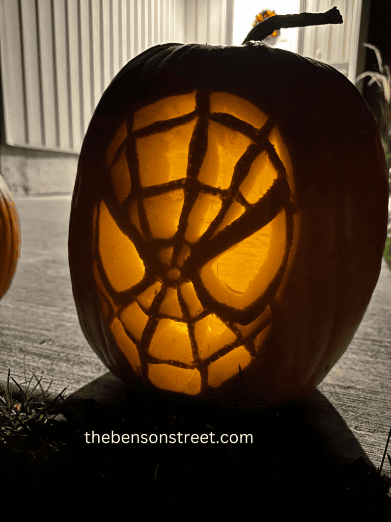 An Amazing Spiderman Carved Pumpkin using a free printable stencil lit up in the dark.