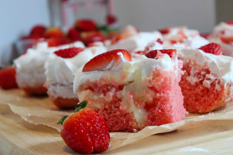 Delcious and easy Strawberry cheesecake poke cake recipe slices on a wood cutting board