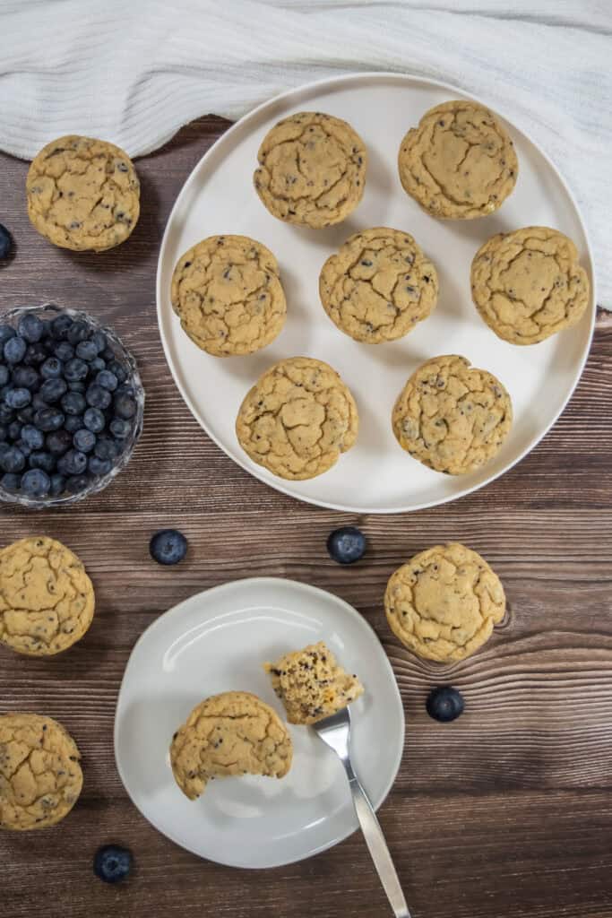 Blueberry muffins made with three ingredients on two plates, one with a bite taken out of it