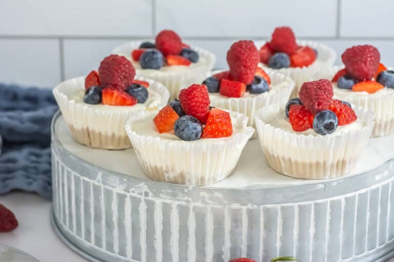 Side shot of a silver platter with mini mixed berry cheesecakes ready to eat