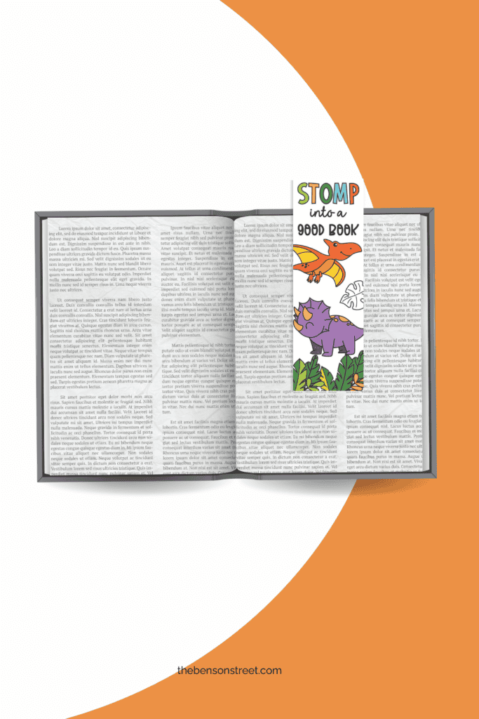 Colored in free printable dinosaur themed bookmarks on an open book flat lay