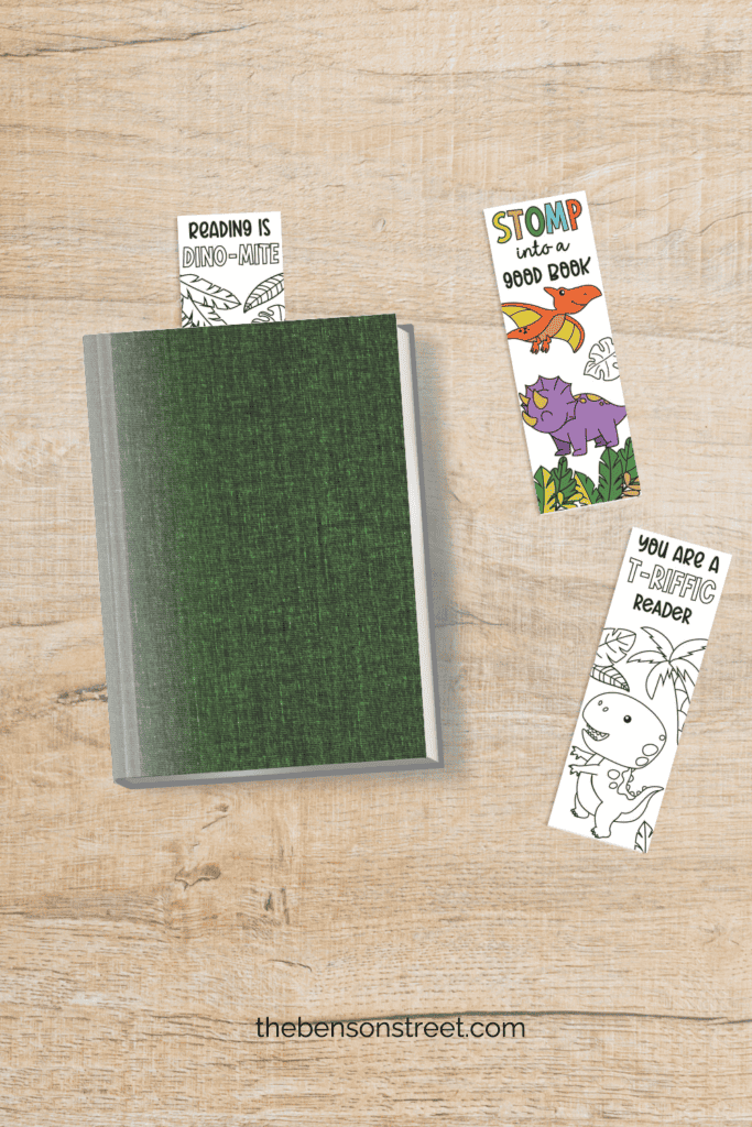 Free to print and color dino themed coloring bookmarks shot from above with one sticking out of a book