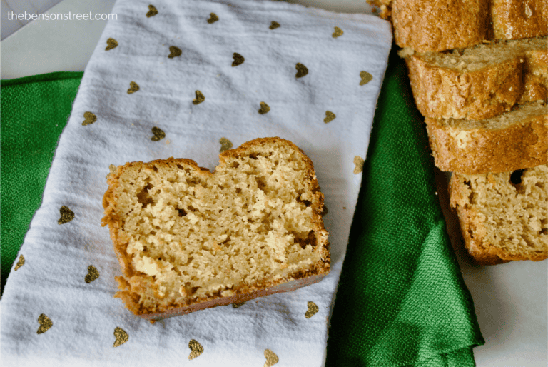 Slice of orange chocolate chip bread on a tea towel with sliced loaf on the side