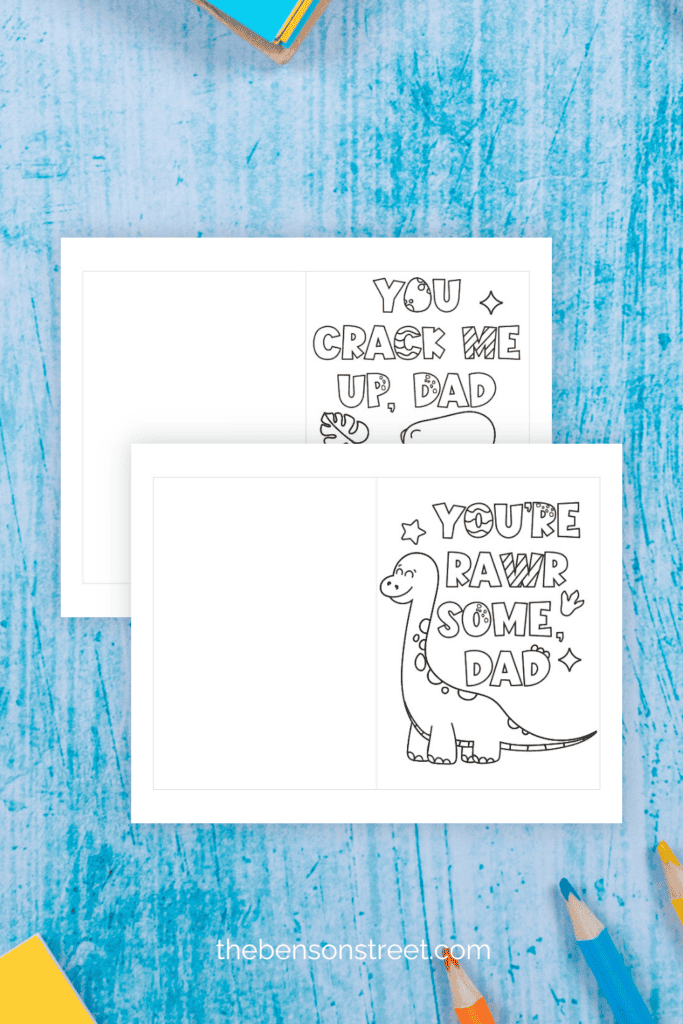 Two printed out sheets with dino father's day cards on a blue background with colored pencils