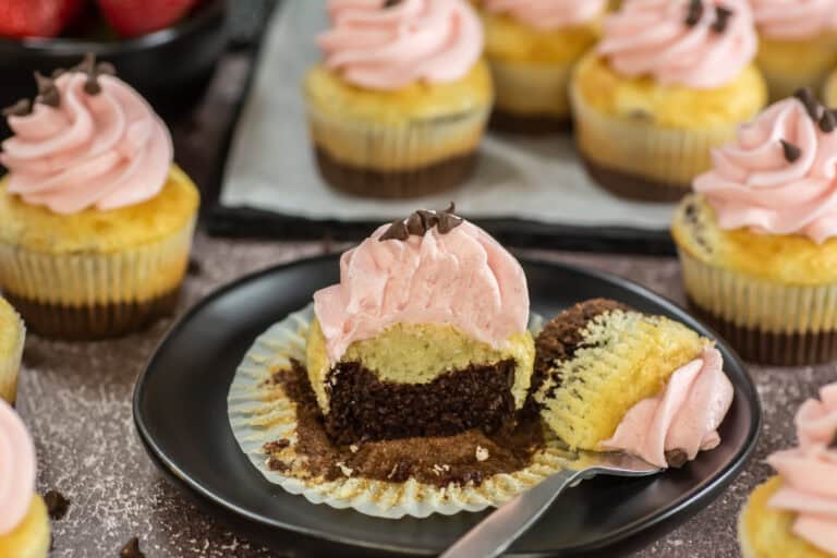A Neapolitan Cupcake on a plate with a bite on a fork next to it