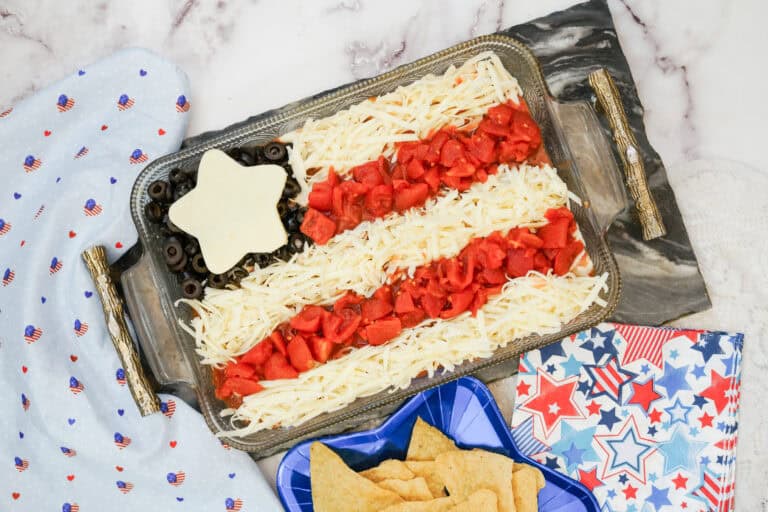 Overhead shot of a pan of Flag taco dip with a plate of chips on the side