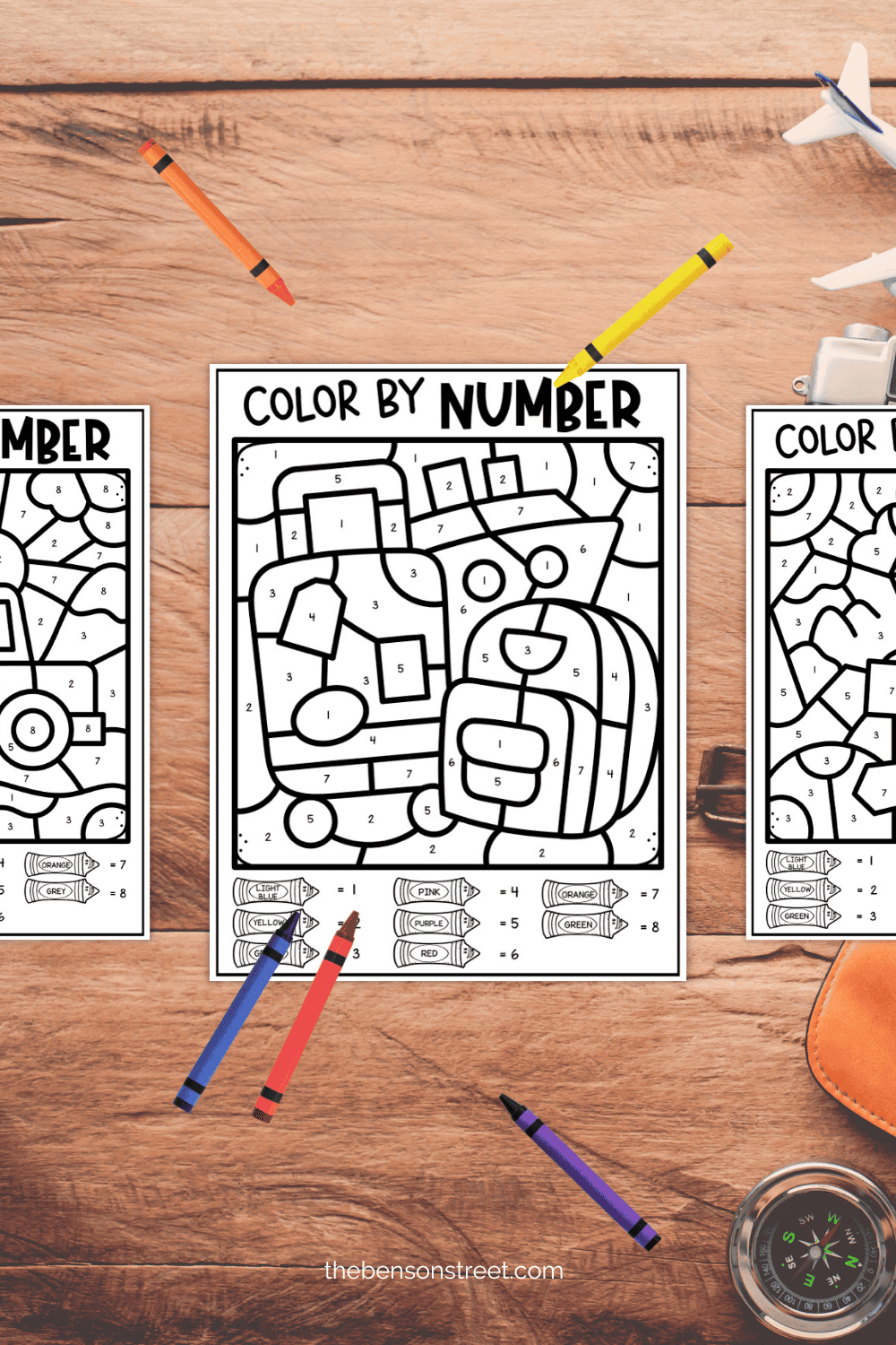 Three color by number sheets with crayons around them to color in on a long trip