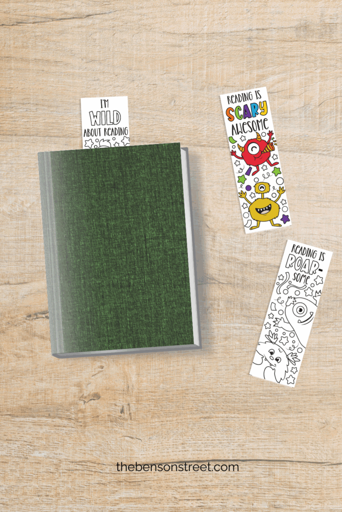 Book with a monster bookmark in it, and two laying on the table next to the book
