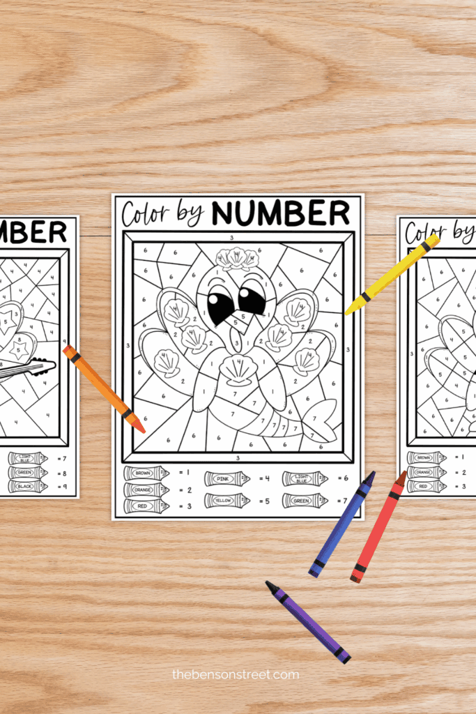 A table with sheets of color by number worksheets for Thanksgiving with crayons around 