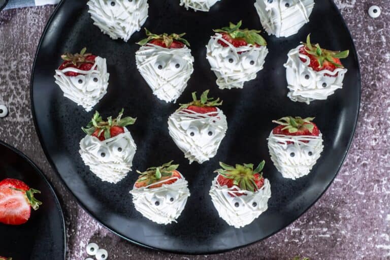 Up close overhead shot of strawberries with white chocolate drizzles to look like mummy bandages