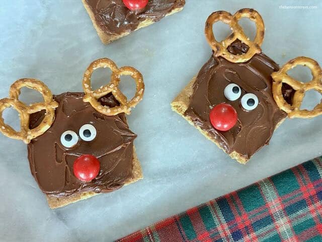 Use candy eyes and pretzels to make reindeer graham cracker treats at thebensonstreet.com
