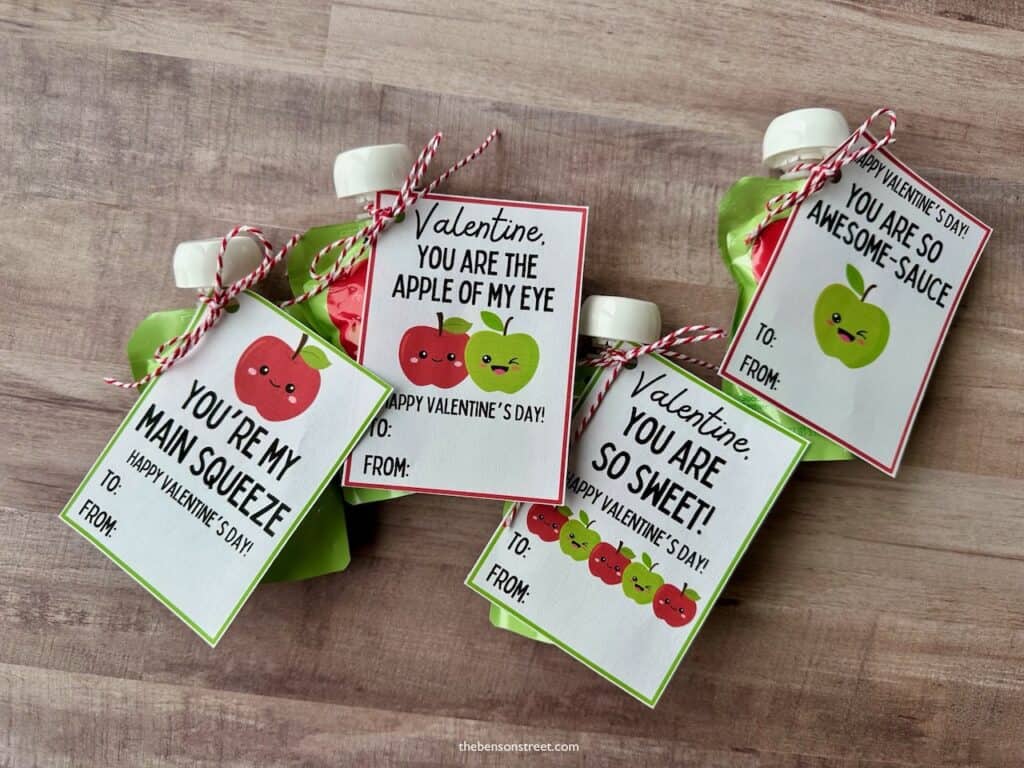 Four applesauce pouches with valentine tags tied to them 