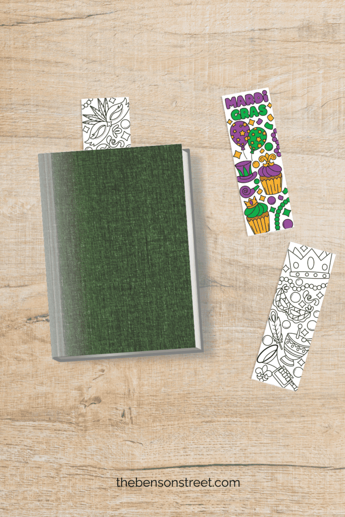 Green book with a bookmark sticking out of the top with two others laying by it on a table