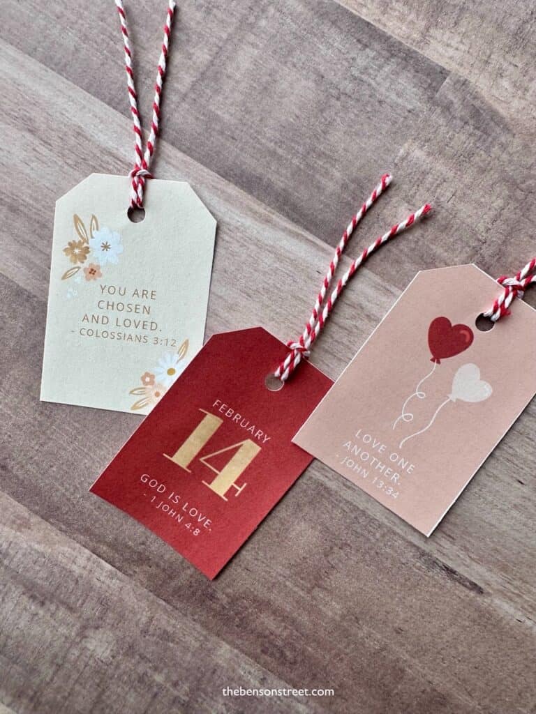 Three tags cut out for Valentine's Day with bible verses on them