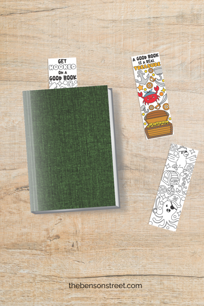A green book with a bookmark sticking out of the top and two other pirate themed bookmarks next to it