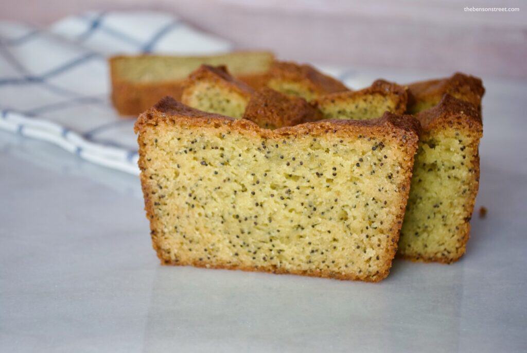 Freshly baked lemon poppy seed cake slices on a white surface, close-up.