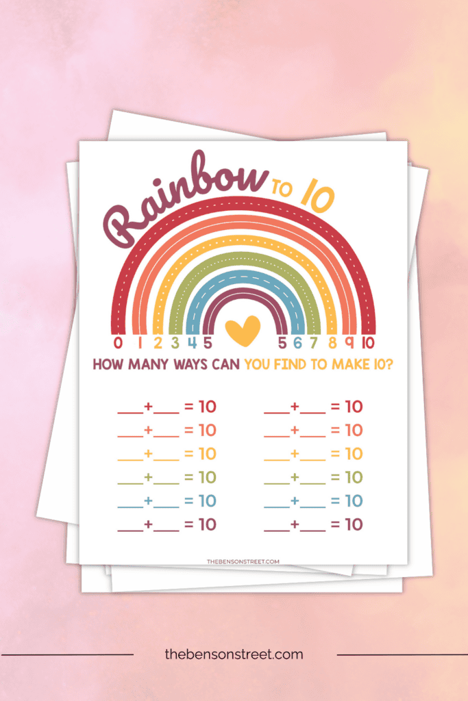 Rainbow to 10 printable additions worksheet on a stack of papers
